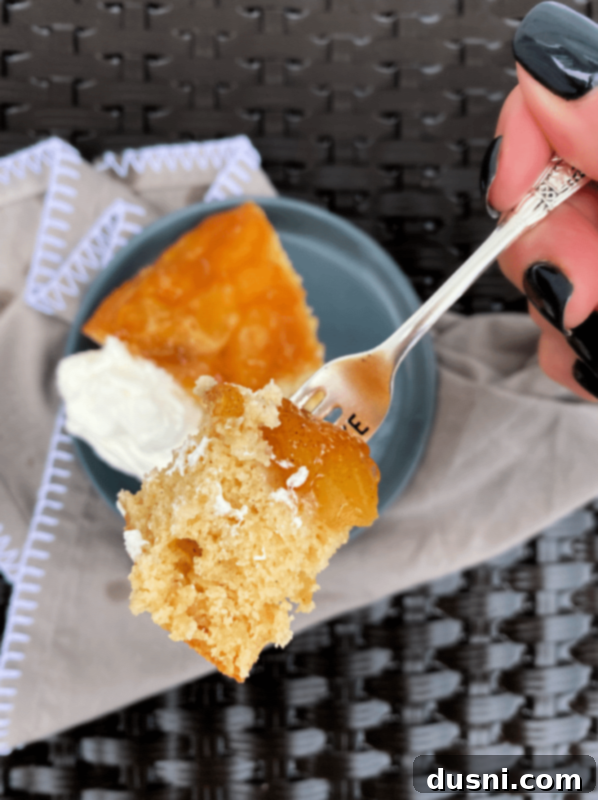 A bite taken out of a slice of Apple Upside Down Cake, showing the moist cake and soft apple texture.