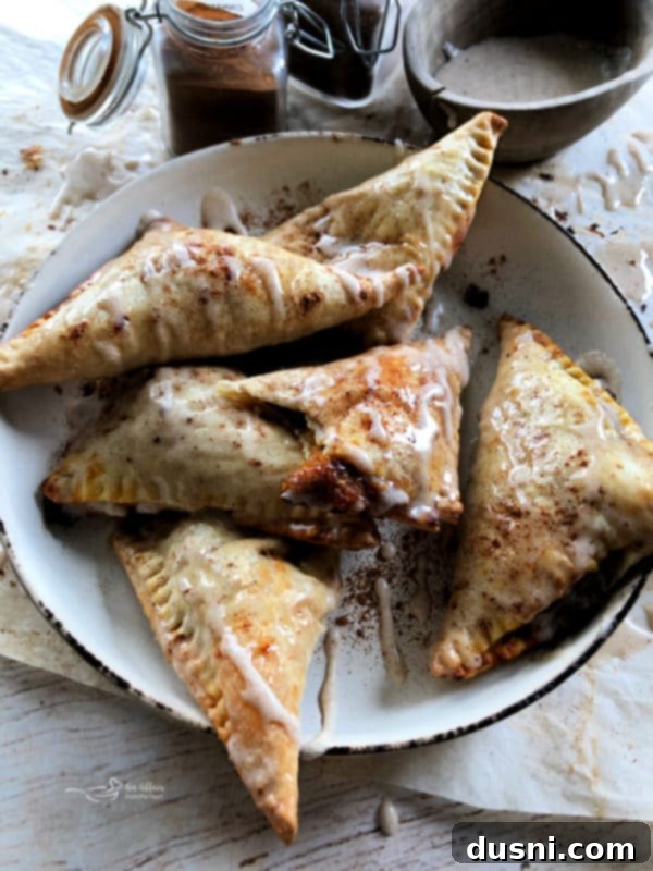 Close-up of golden brown pumpkin pie turnovers on a baking sheet