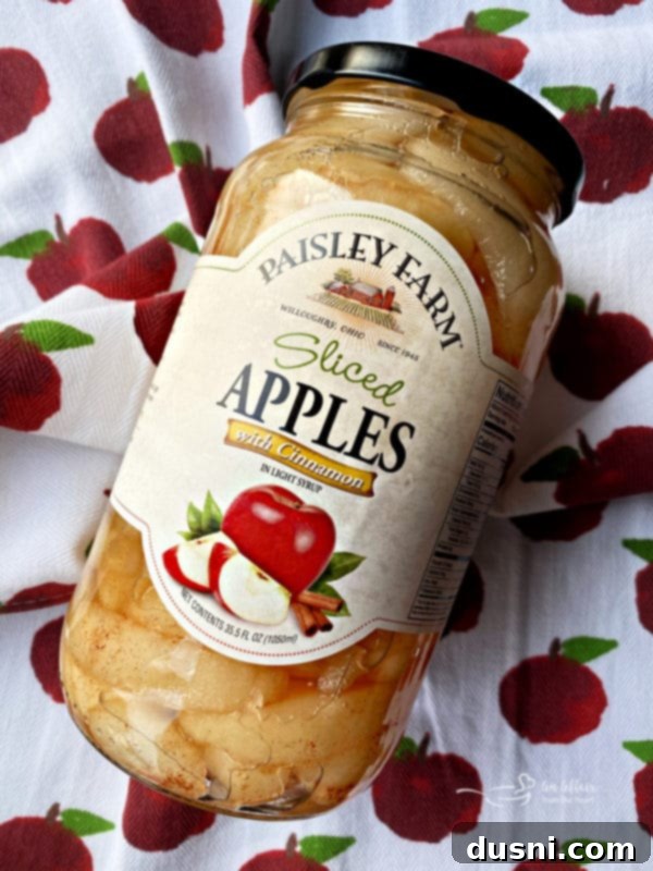 Effortless Apple Crumble Bars 3 Close-up of a pan of fresh Apple Bars, generously drizzled with glaze, featuring Paisley Farm Sliced Apples with Cinnamon and a golden-brown crust.