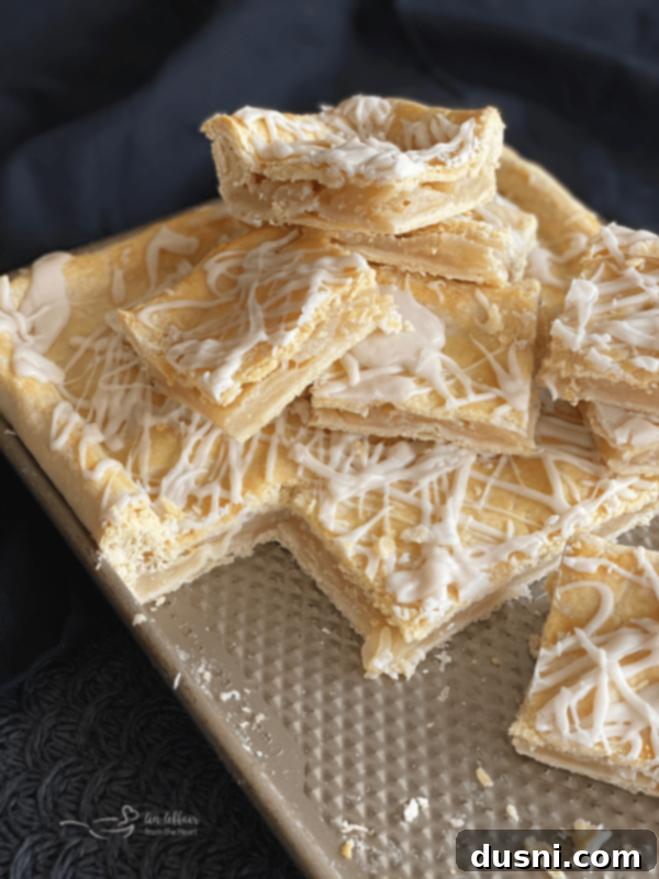 Effortless Apple Crumble Bars 4 Homemade Apple Bars cooling on a cookie sheet after baking, showing the golden-brown flaky crust and glistening glaze.