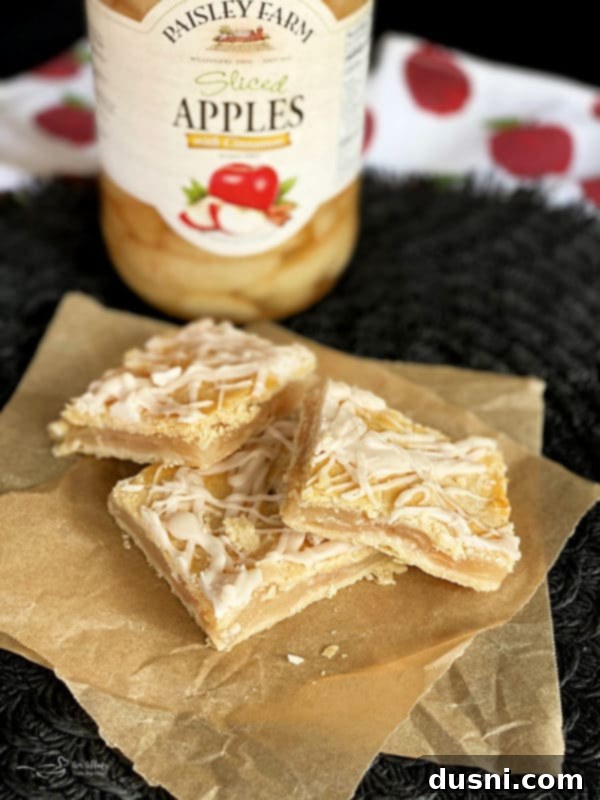 Effortless Apple Crumble Bars 7 A full pan of freshly baked and glazed Apple Bars made with Paisley Farm apples, sliced and ready to be served, on a wooden surface.