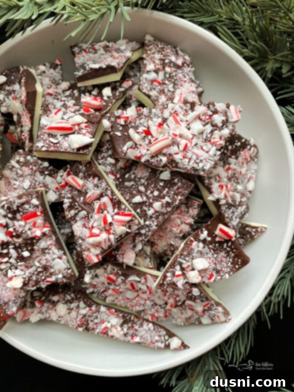 Serving bowl filled with beautiful white and dark chocolate peppermint bark pieces, topped with crushed candy canes, ready for holiday festivities