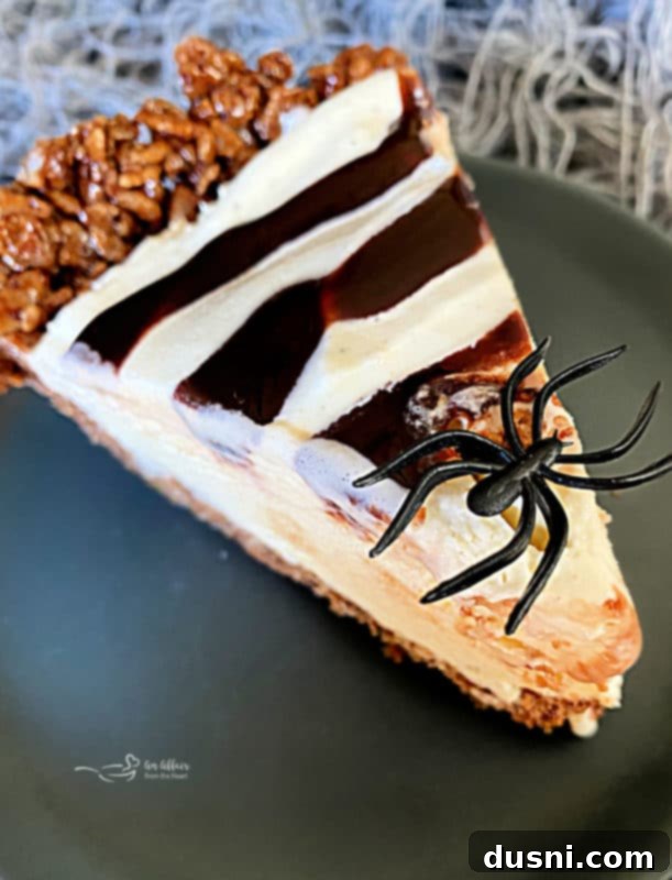Top-down view of Spider Web Ice Cream Pie decorated with chocolate syrup web and plastic spiders