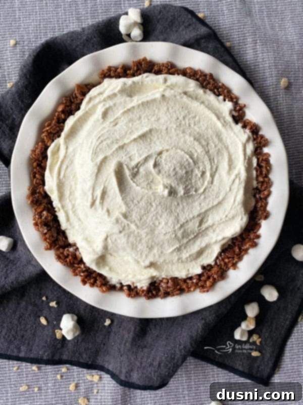 Preparing the Chocolate Marshmallow Pie Crust with vanilla ice cream in a white pie plate