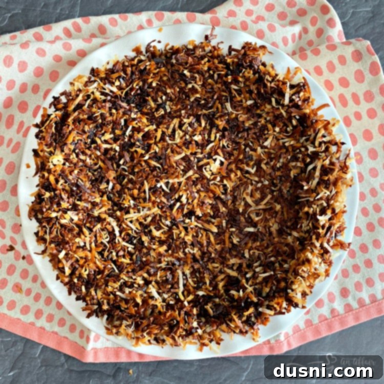 Pressing toasted coconut into a pie plate to form the crust
