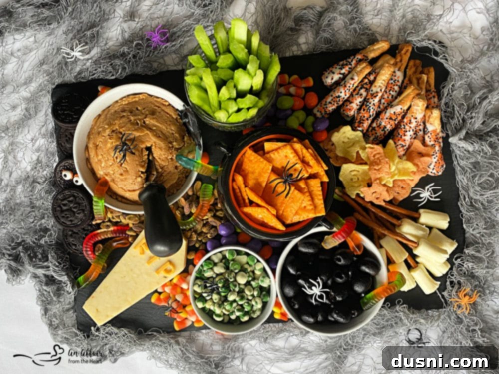 A Hauntingly Delicious Halloween Spread Sweet Savory and Peanut Butter Dip 2 A vibrant Halloween snack board overflowing with sweet and savory treats, including cheese crackers, celery, witch brooms, and candy, centered around a bowl of peanut butter dip.