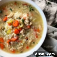 Close up of Instant Pot Chicken & Rice Soup in a white bowl, garnished with fresh herbs