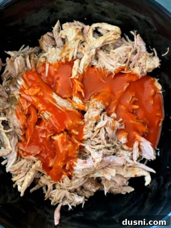 Spicy Slow Cooker Buffalo Pulled Pork with Cooling Celery Slaw 10 Shredded pork simmering in sauce in slow cooker
