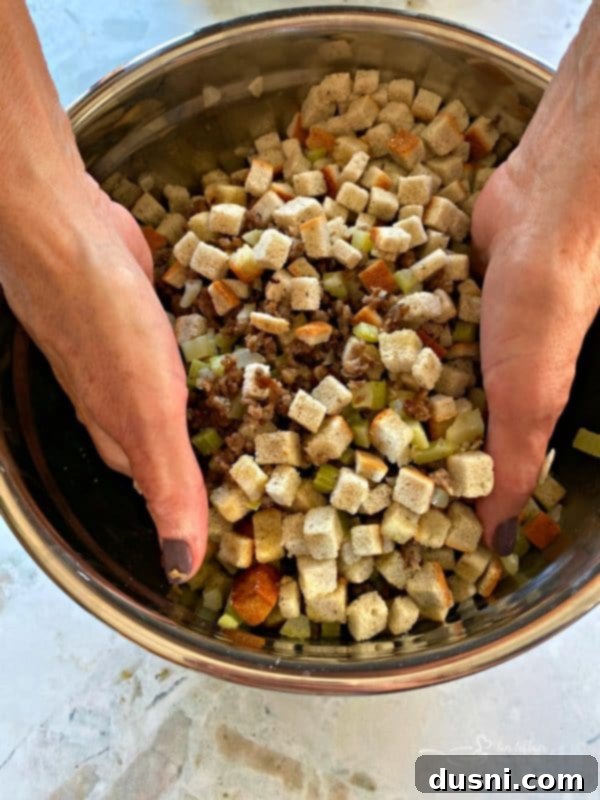 Mom's Pork Sausage and Sage Dressing 7 The author's mom's hands mixing the sausage and sage stuffing in a large bowl, demonstrating the perfect consistency.