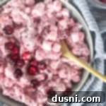 Close up of Cranberry Fluff Salad in bowl with light bluish background, indicating a serving.