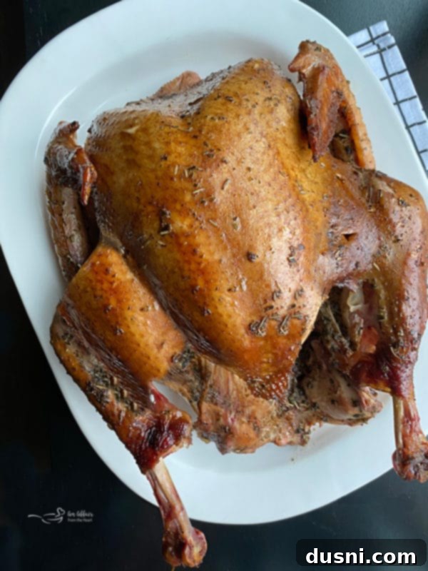 Perfectly smoked turkey on a white platter, garnished with fresh herbs, ready to be served