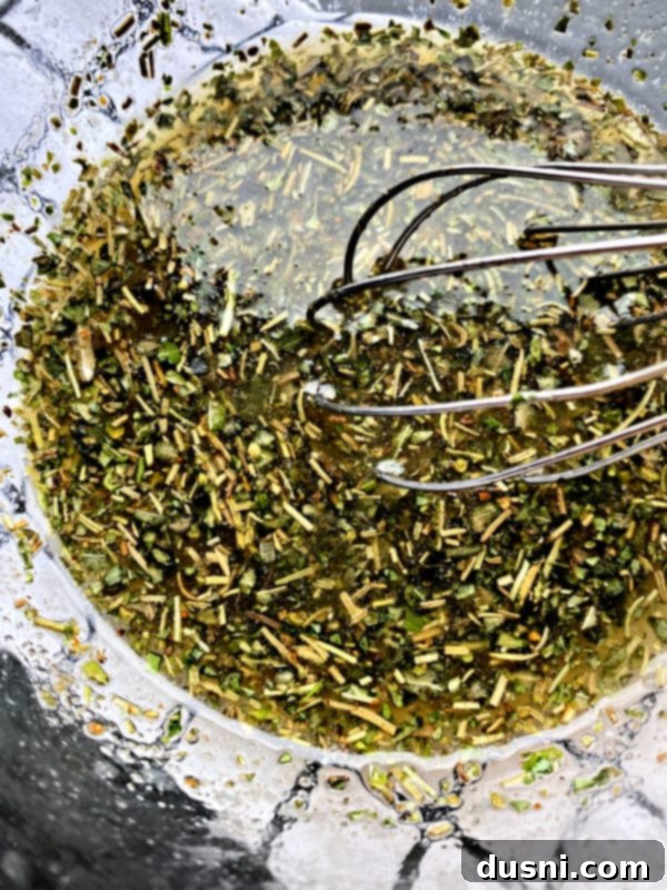 Close-up of a bowl of melted butter mixed with various herbs and spices for the turkey rub