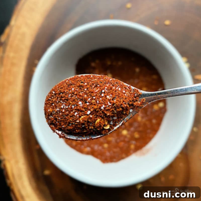Homemade Chili Seasoning in a white bowl with a spoon, highlighting the rich colors of the spices.