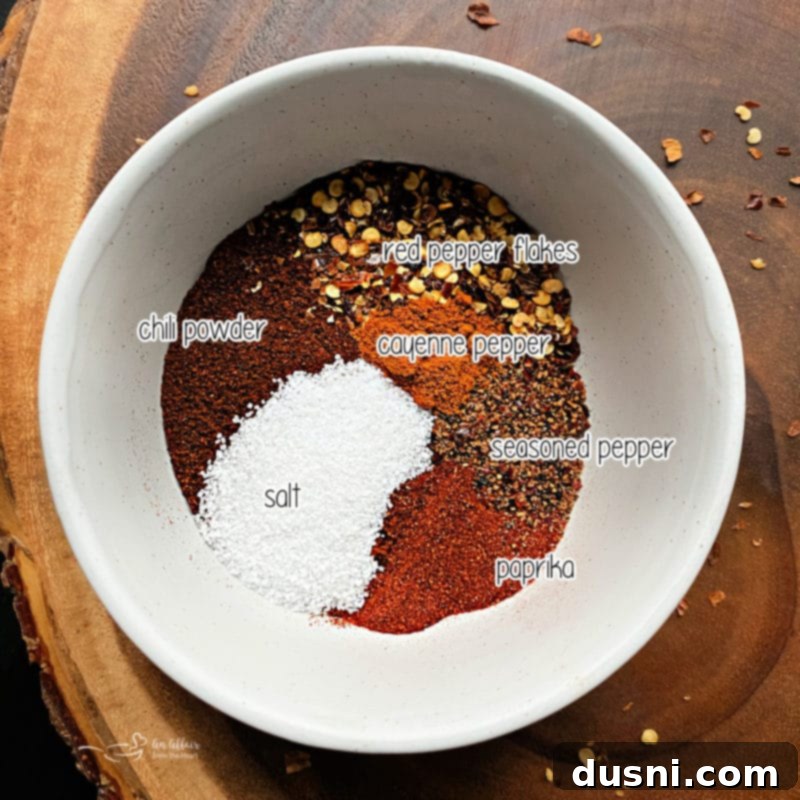 A bowl of homemade chili seasoning blend with text overlay, showing off the rich brown and red hues of the spices, ready to be mixed.