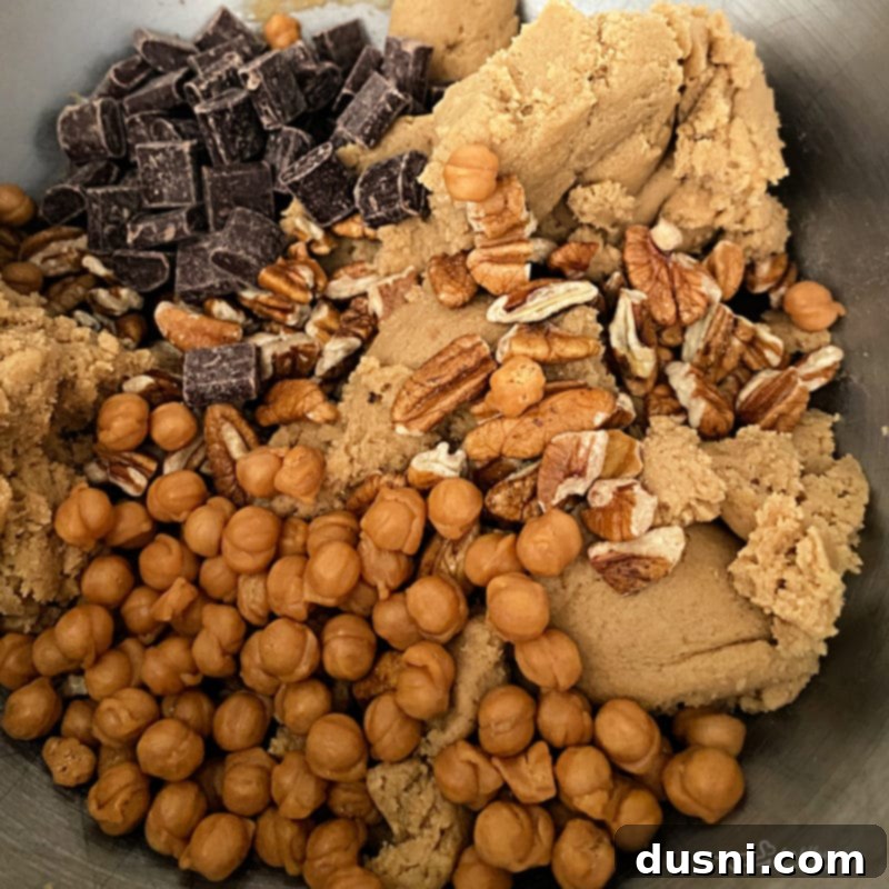 Gooey Turtle Delights 5 Cookie dough being mixed in a bowl with visible chocolate, caramel, and pecans.