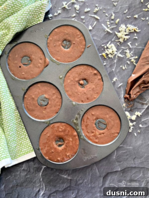 Donut batter being piped into a donut pan.