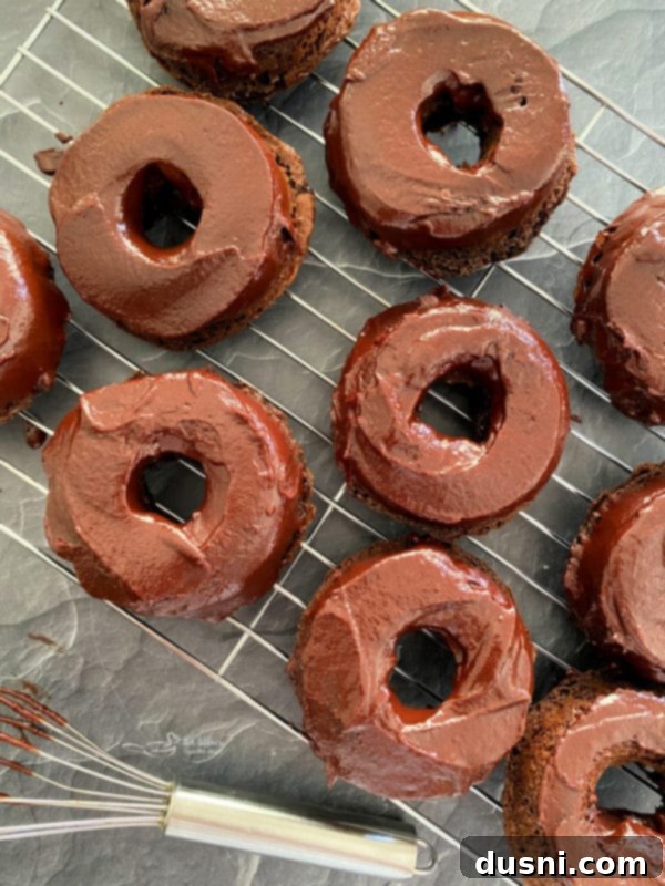 Chocolate ganache being drizzled over baked chocolate kraut donuts.