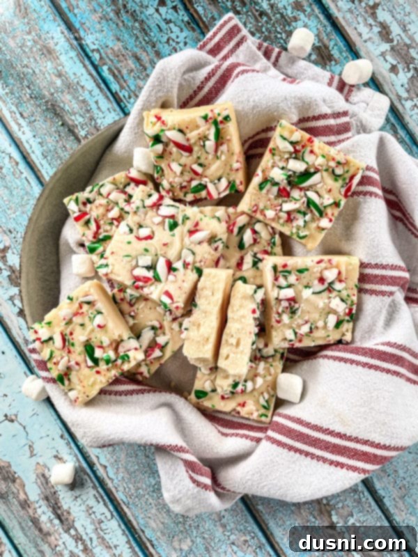 Several squares of white chocolate peppermint fudge on a piece of parchment paper.