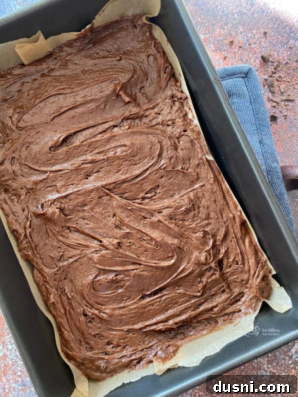 Cookie Dough Brownie Dream 12 Brownie batter spread evenly into a parchment-lined baking dish, ready for the oven.