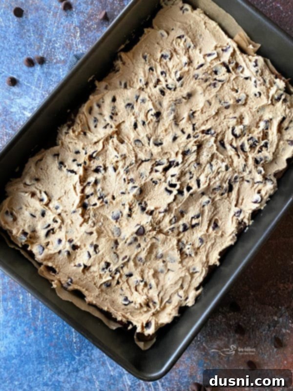 Cookie Dough Brownie Dream 14 Edible cookie dough being spread over chilled brownies using a rubber spatula.
