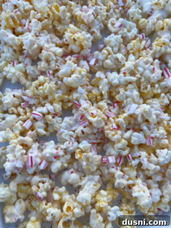 A bowl of peppermint candy coated popcorn with a few loose candy canes.