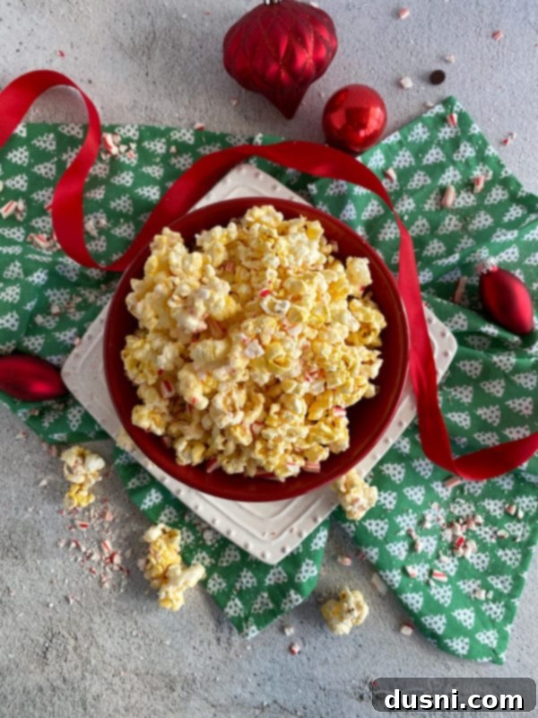 Peppermint Candy Coated Popcorn in a bowl with two candy canes.