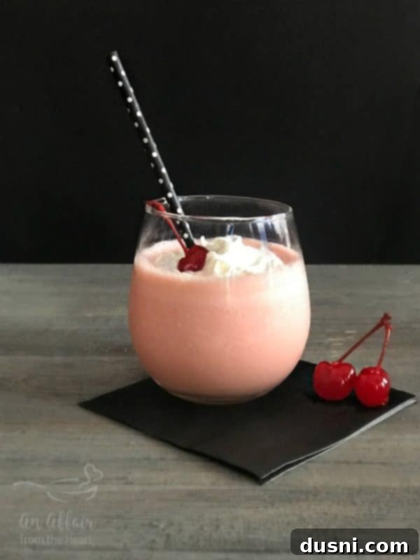 Pink Squirrel cocktail garnished with a cherry and whipped cream.