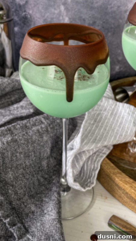 Close-up of a single Grasshopper Cocktail, showcasing its vibrant green hue and whipped cream topping.