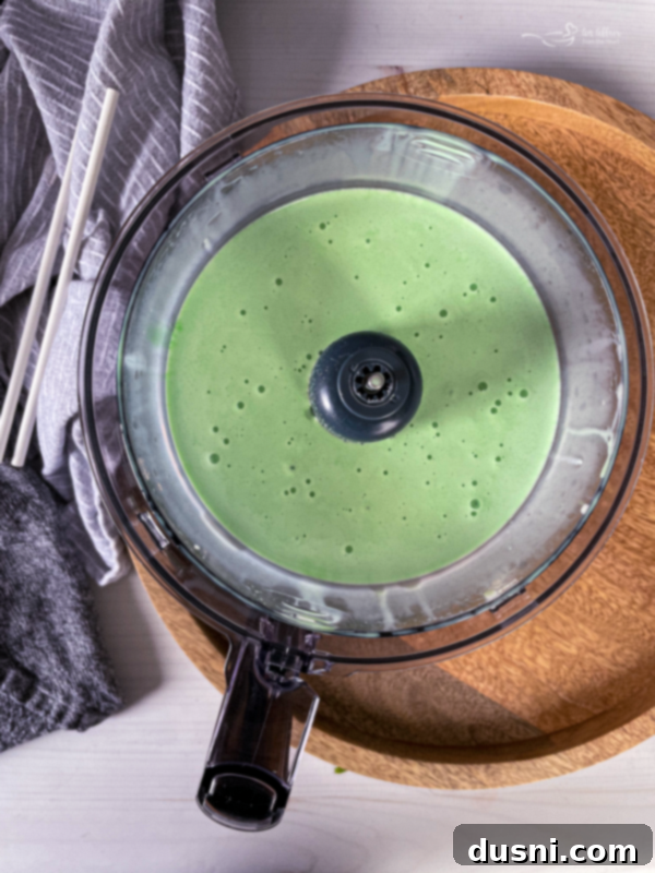 Pouring green Crème de Menthe into a blender with vanilla ice cream for a Grasshopper Cocktail.