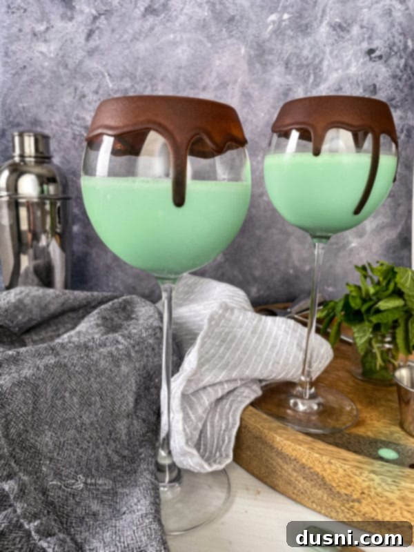 Two Grasshopper Cocktails topped with generous whipped cream and chocolate shavings.