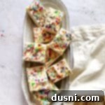 Frosted sugar cookie bars stacked on a white serving plate.