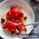 Close up of a fork taking a bite of the cherry dessert.