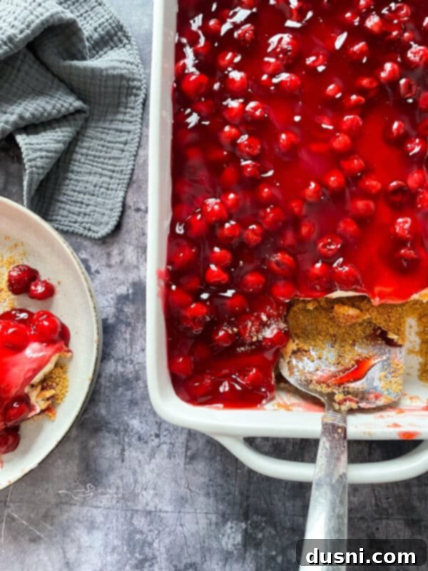 A rectangular baking dish filled with the completed no-bake cherry dessert, ready for chilling and serving.
