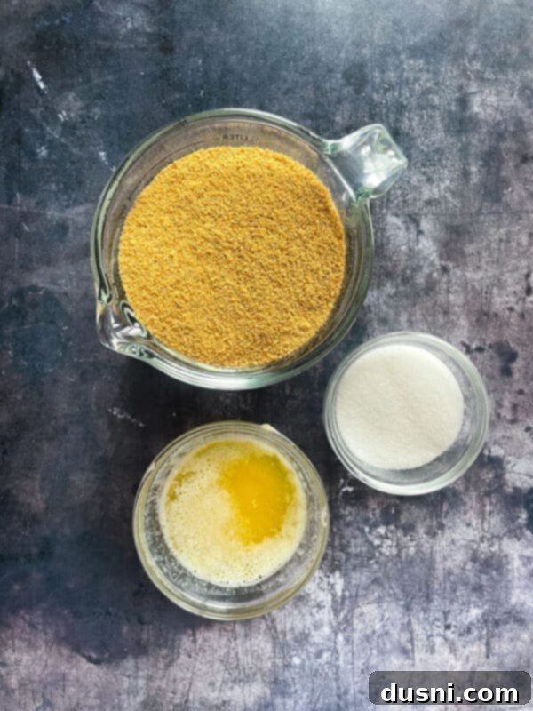 Individual bowls containing graham cracker crumbs, melted butter, and granulated sugar, the ingredients for the crust.