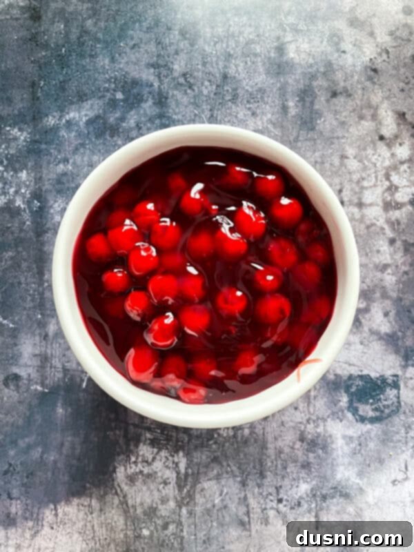 Two cans of cherry pie filling, the final layer for the no-bake cherry dessert.