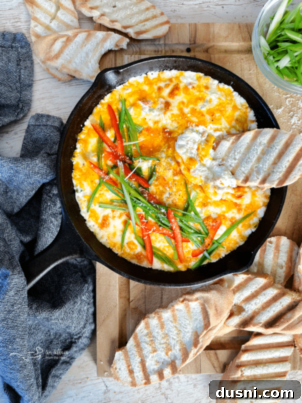 Slow Cooker Crab Dip in a bowl with a spoon, ready to be served, garnished with fresh herbs and bell peppers.