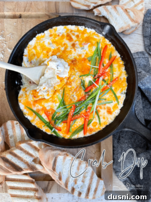 A beautifully presented Slow Cooker Crab Dip in a crockpot, surrounded by dippers and garnished with fresh herbs.