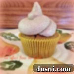 Side view of a single pumpkin cupcake with cinnamon buttercream frosting on a multicolored plate.