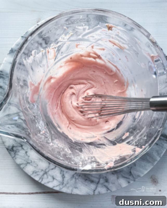 Strawberry cream cheese frosting being mixed in a bowl with an electric mixer