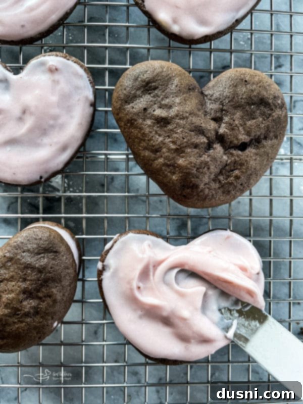 Spreading strawberry cream cheese filling onto one half of a chocolate whoopie pie