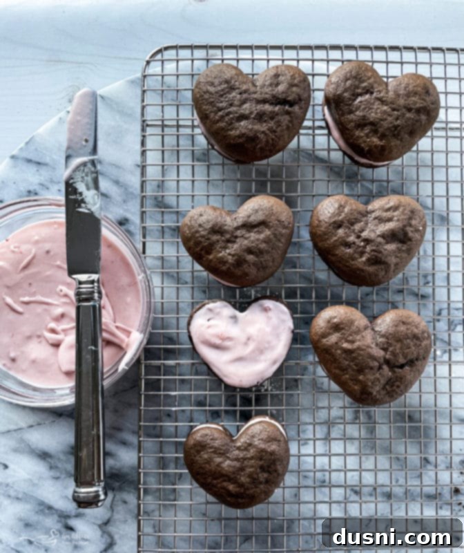 Placing the second chocolate whoopie pie half on top of the strawberry cream filling