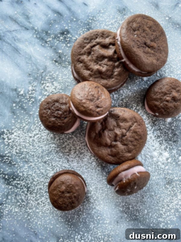 Chocolate strawberry whoopie pies dusted with powdered sugar on a serving plate