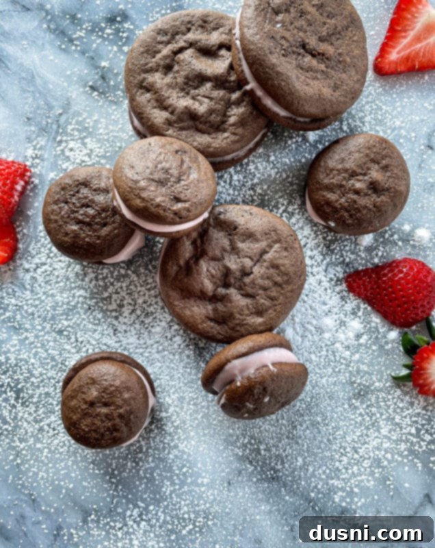 Chocolate strawberry whoopie pies dusted with powdered sugar and garnished with fresh strawberries