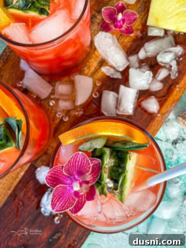 Radiant Island Fizz 2 A vibrant Tropical Sparkling Cocktail garnished with pineapple and orange slices, sitting on a wooden surface.