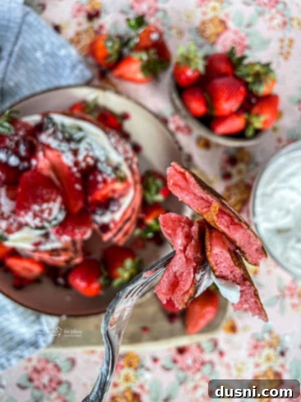 A close-up of strawberry pancakes in a stack.