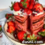 Close up of stacked Strawberry pancakes loaded with strawberries on top
