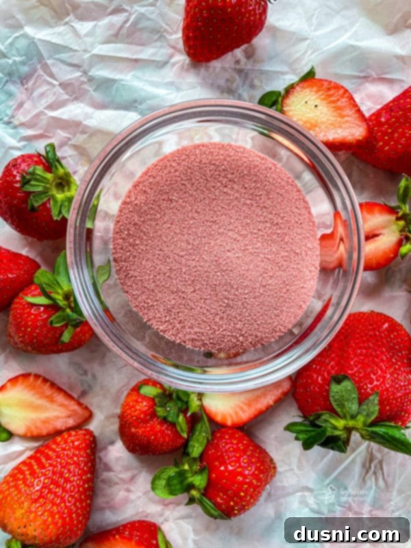 A bowl of sliced fresh strawberries being coated with strawberry Jell-O mix.