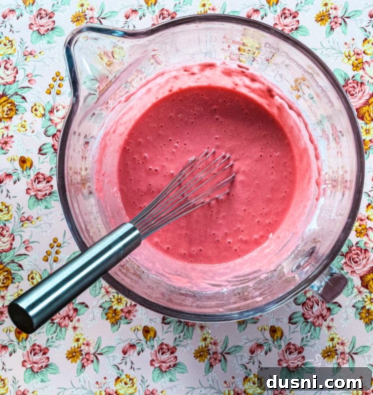 Wet ingredients (eggs, milk, oil) for pancakes being whisked in a bowl.
