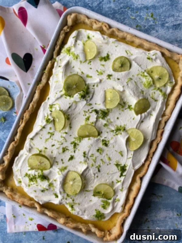 Zesty Key Lime Sheet Pie 2 Delicious Key Lime Slab Pie with fresh lime slices and whipped cream on a large serving board.
