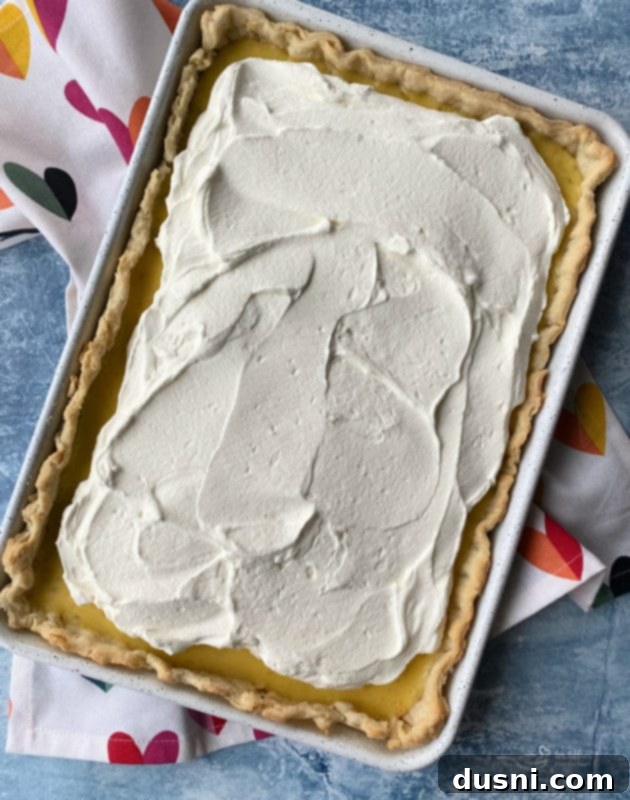 Zesty Key Lime Sheet Pie 12 Whipped cream being spread over the chilled Key Lime Slab Pie.